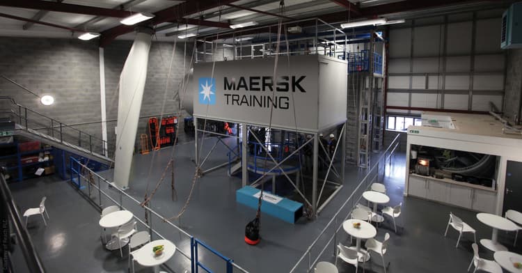 indoor training facility branded with "Maersk Training," featuring a high structure equipped for practical exercises, likely simulating industrial or maritime environments. The space includes seating areas, indicating a blend of training and collaborative zones.
